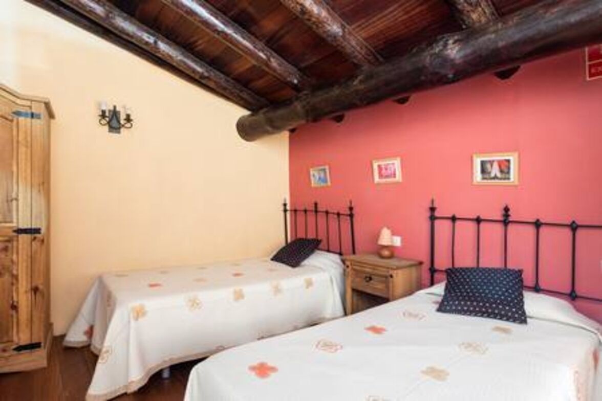 Un dormitorio con dos camas, muebles de madera y una pared de acento roja.