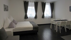 A modern hotel room with a bed, a desk, and chairs. - Hotel201 (Gablitz)