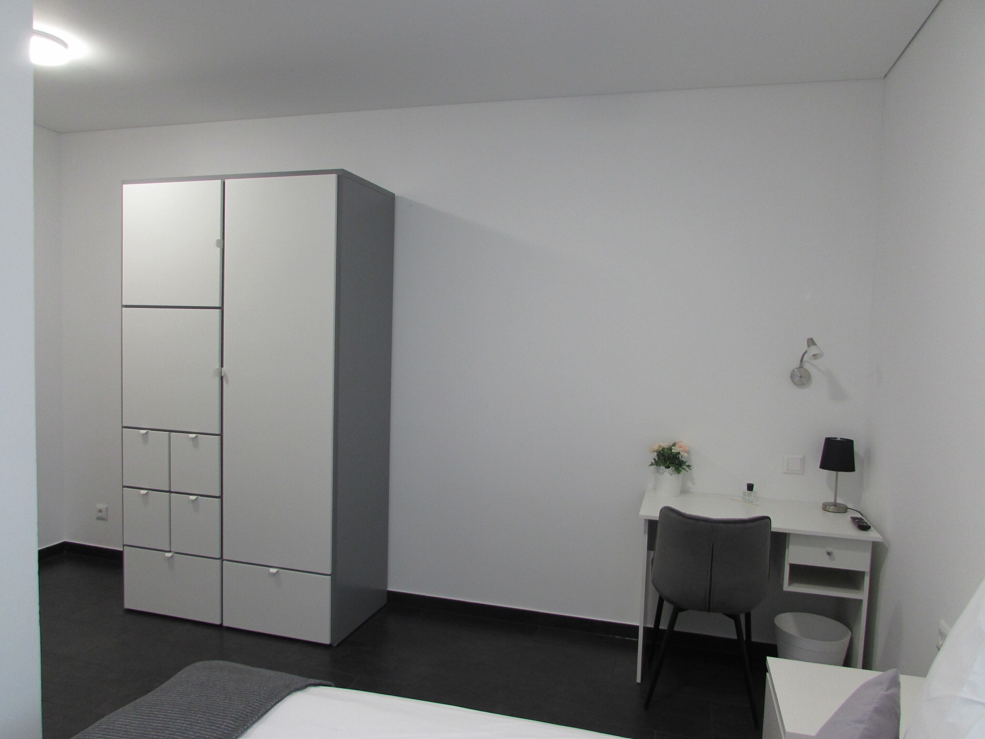 Une chambre à coucher moderne avec un lit, un bureau et une armoire.