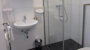 A modern bathroom with a glass-enclosed shower, a sink, and a toilet. - Hotel201 (Gablitz)