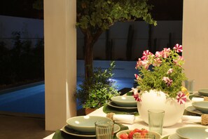 A dining table set with plates, bowls, and a vase of flowers. - Luxury Beach House w / Heated Pool + Jacuzzi (Albufeira)