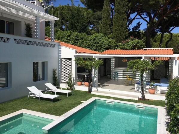 A modern house with a swimming pool, outdoor seating, and a covered patio area. - Luxury Beach House w / Heated Pool + Jacuzzi (Albufeira)