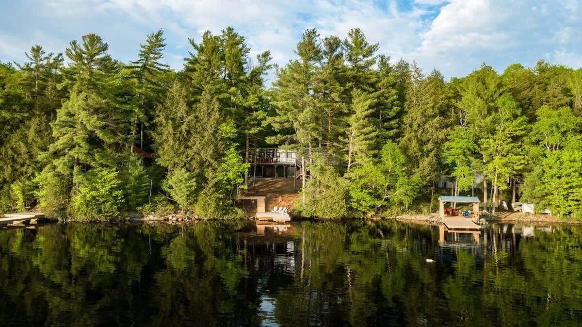 Mökki, jonka ympärillä on tiheä metsä ja jonka lähellä on rauhallinen järvi.