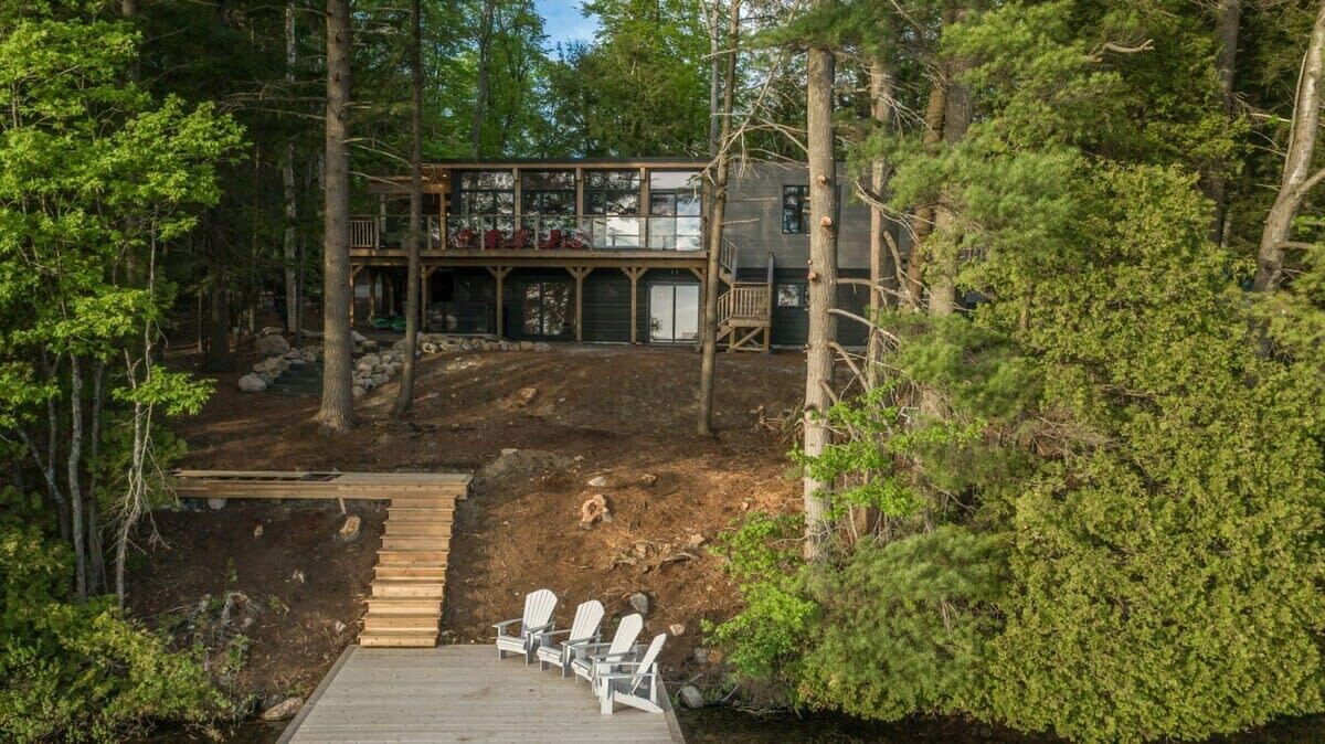 A cabin with a deck, surrounded by trees.