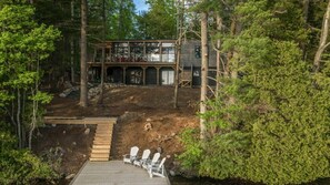 A cabin with a deck, surrounded by trees.