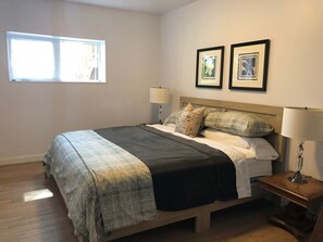 A bedroom with a bed, two bedside lamps, a nightstand, and two framed pictures on the wall.