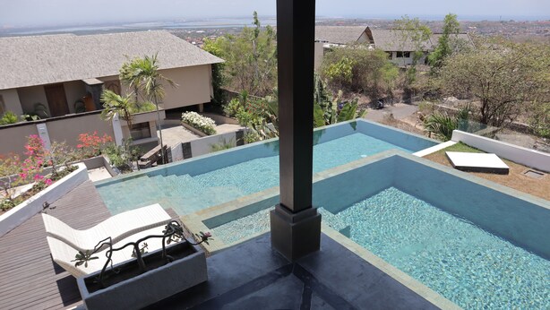 A swimming pool with lounge chairs and a view of a residential area. - The Bukit Ocean View Villa Jimbaran (Jimbaran)