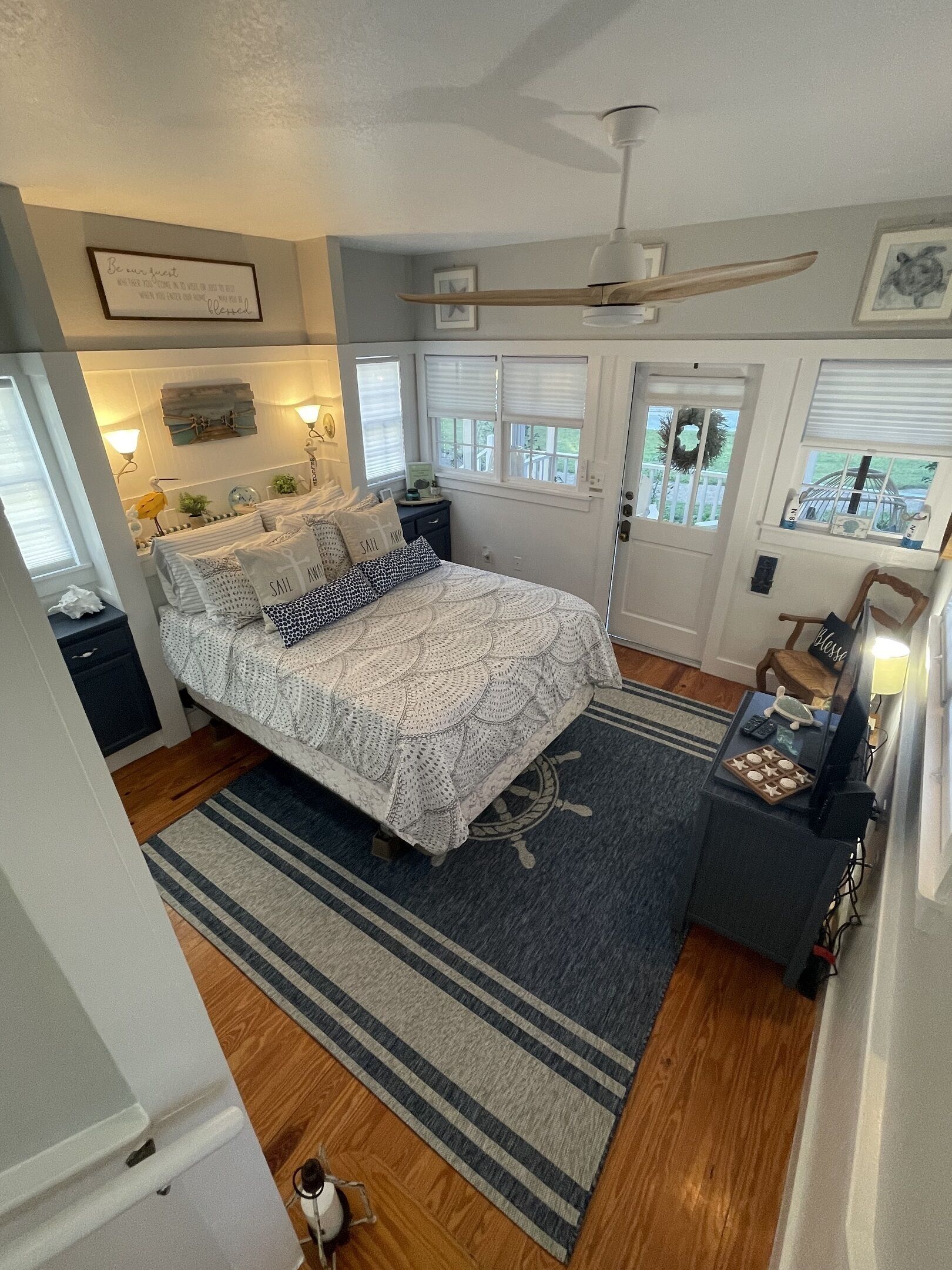 A bedroom with a bed, a nightstand, a dresser, a window with blinds, a ceiling fan, and a rug.