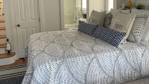 Une chambre à coucher avec un lit, une porte, une fenêtre et un luminaire fixé au mur.