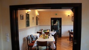Un comedor con una mesa dispuesta para cuatro personas, sillas de madera y un mantel blanco.