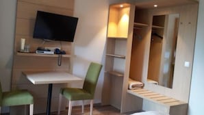 Una habitación de hotel con escritorio, una silla, televisor, armario y espejo.