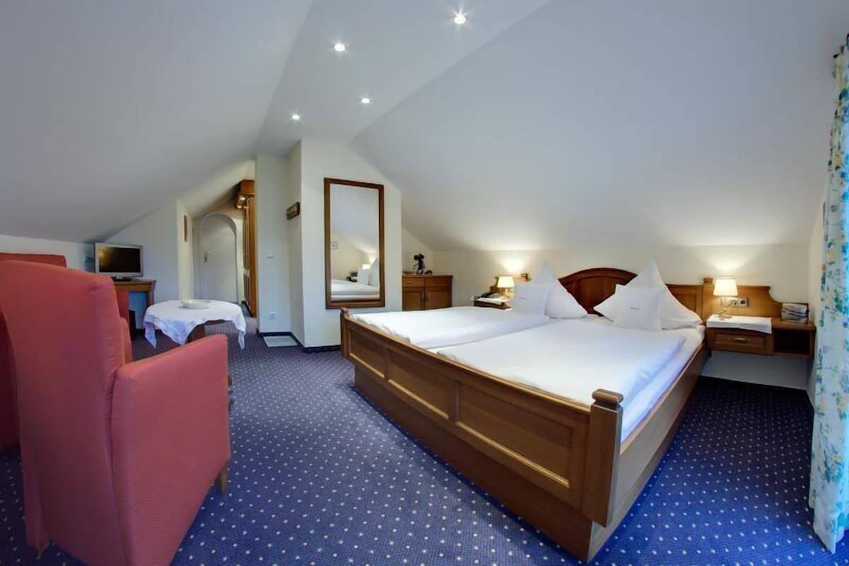 Una habitación de hotel con una cama grande, un escritorio, una silla y un espejo.