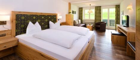 A hotel room with a large bed, a desk, a chair, and a TV.