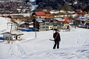 Un centro de esquí con telesilla, pistas cubiertas de nieve y edificios al fondo.