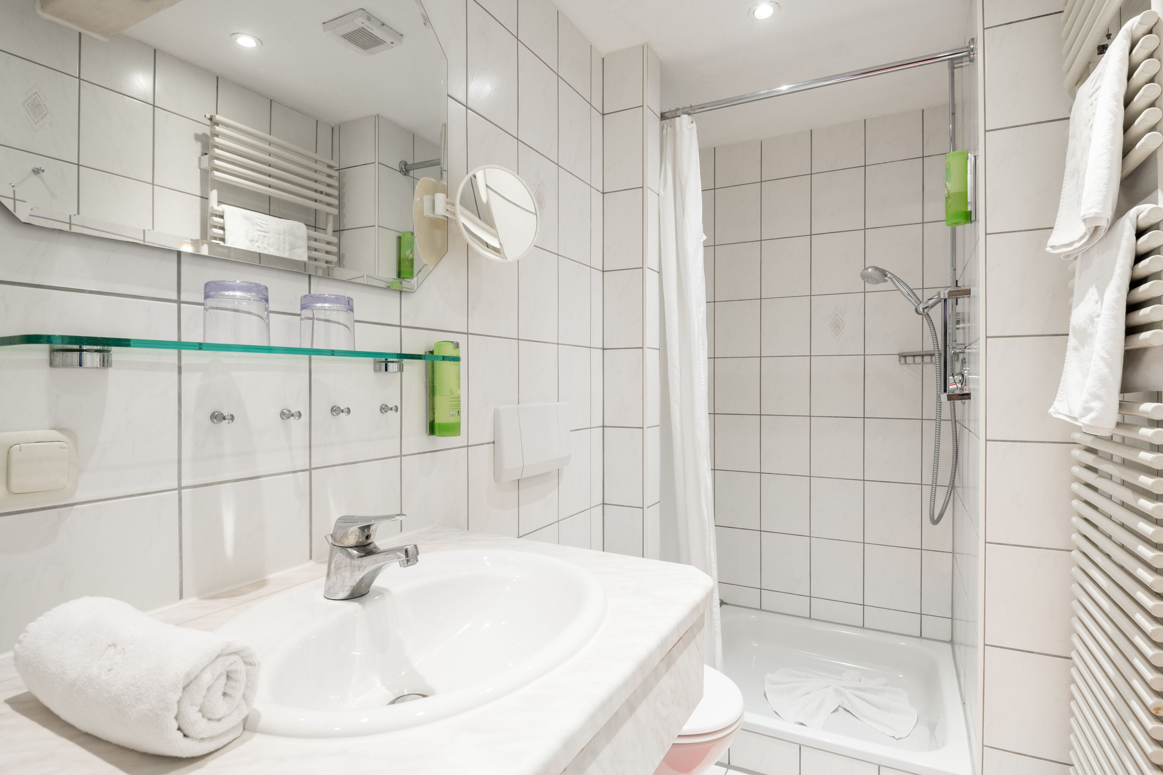 A modern bathroom with a white sink, mirror, and shower.