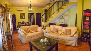A living room with two sofas, a coffee table, a staircase, and a bookshelf. - Andalusian village family house (Peñaflor)