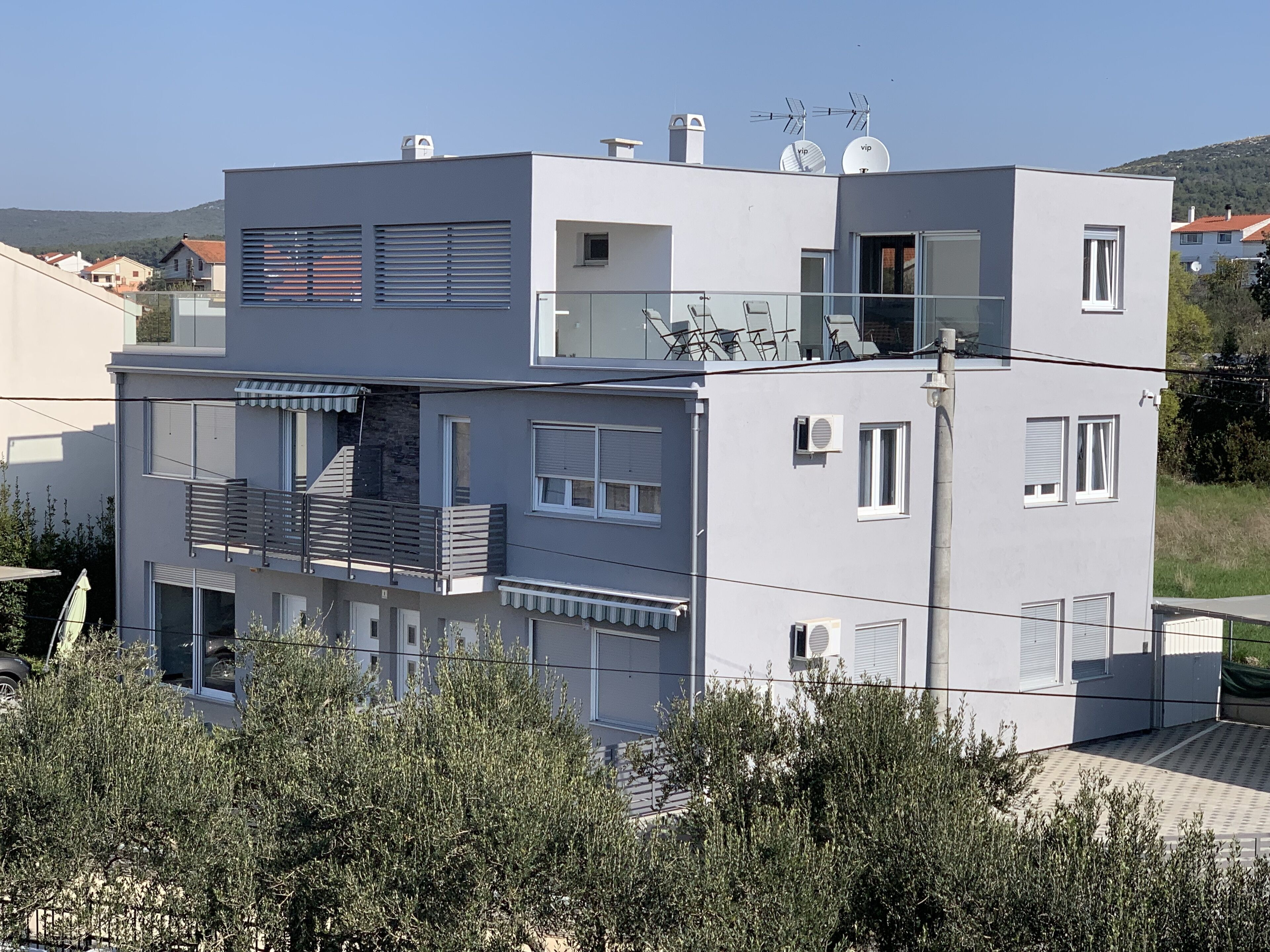 Un edificio residenziale a più piani con balconi, parabole e cielo sereno.