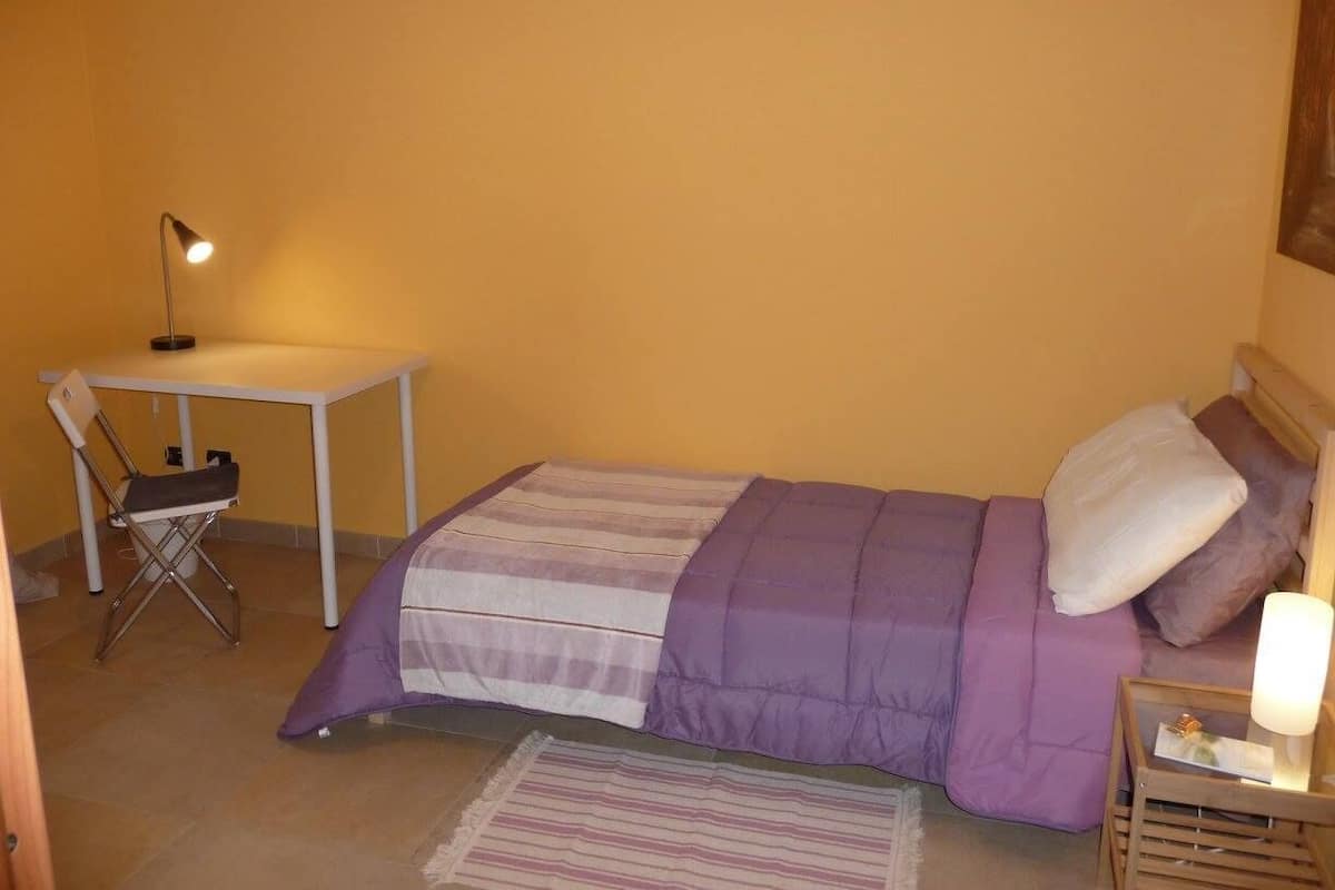 Un dormitorio pequeño con cama, escritorio y silla.
