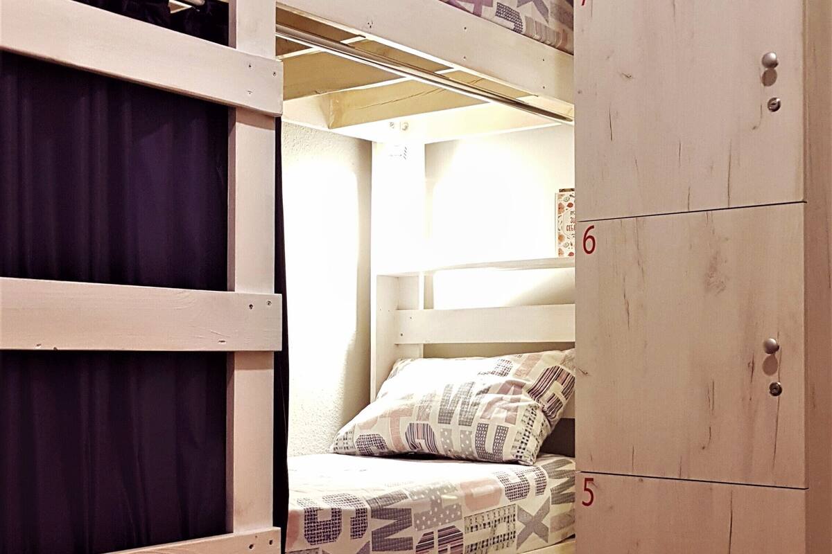 A bunk bed room with a wardrobe and a window.
