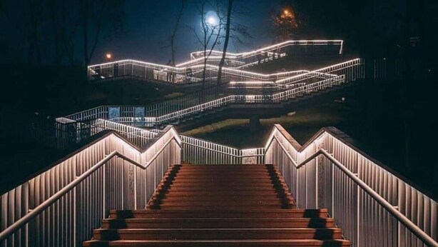 A nighttime view of a staircase leading up to a building with illuminated railings and a moon in the background. - Bulgakoff Hostel (Kyiv)