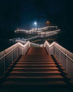 A nighttime view of a staircase leading up to a building with illuminated railings and a moon in the background. - Bulgakoff Hostel (Kyiv)