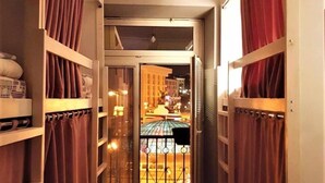 A narrow corridor with bunk beds on either side, leading to a balcony with a railing. - Bulgakoff Hostel (Kyiv)