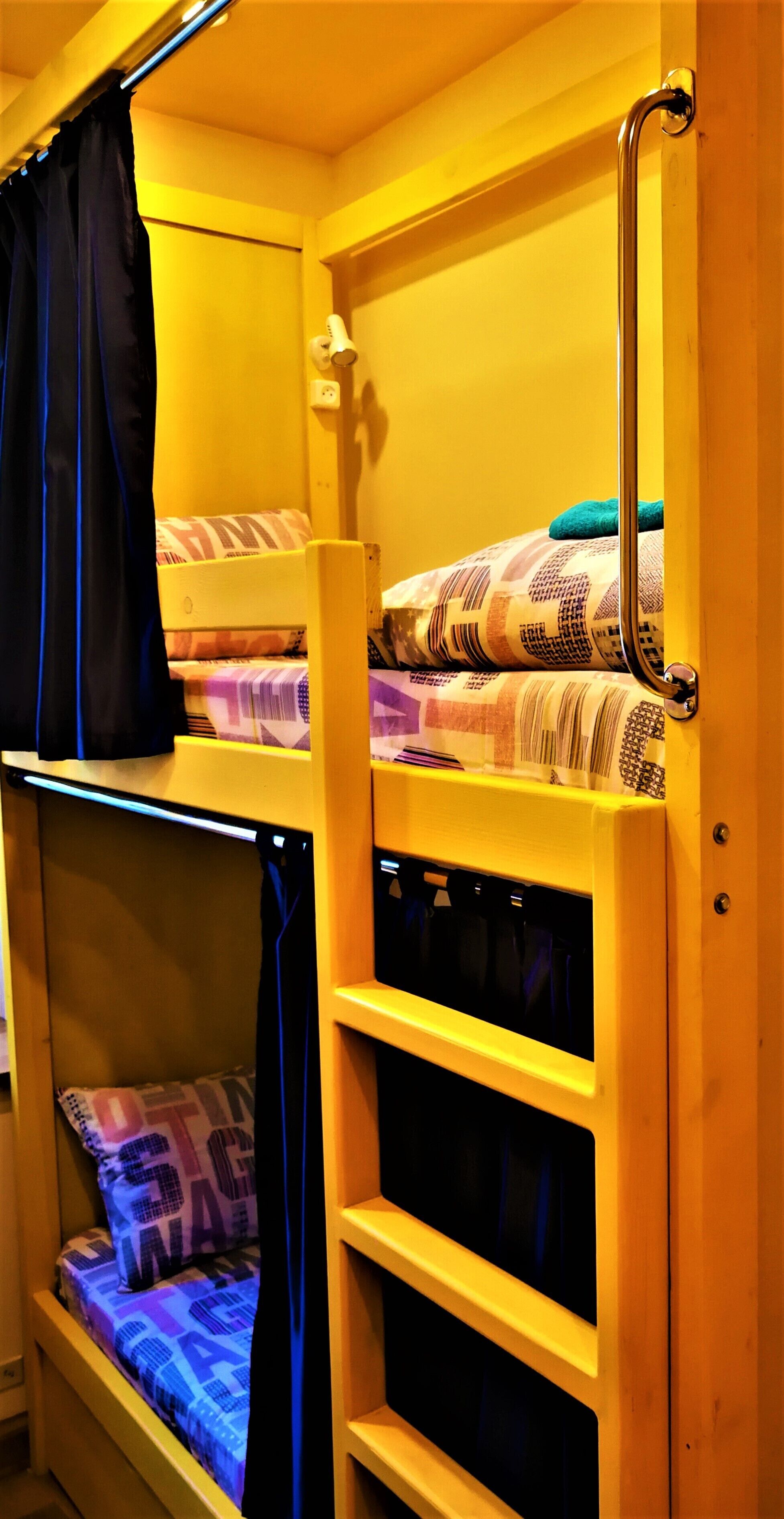 A bunk bed room with a headboard, a small shelf, and a curtain.
