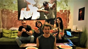 A group of people sitting on a green sofa in a room with a wooden floor, a laptop on a table, and a painting on the wall. - Bulgakoff Hostel (Kyiv)