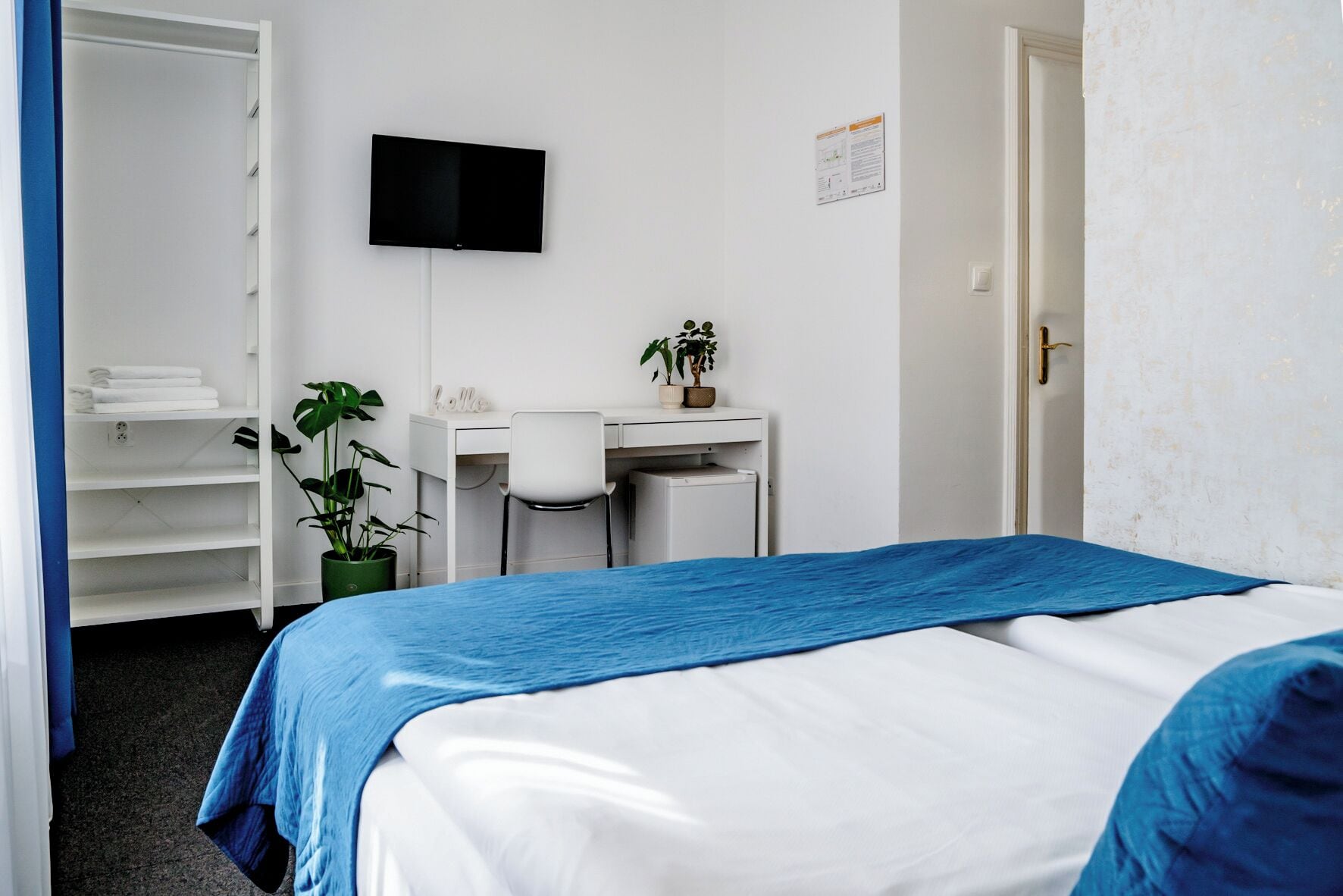 A bedroom with a bed, a desk, a chair, a television, and a wardrobe.