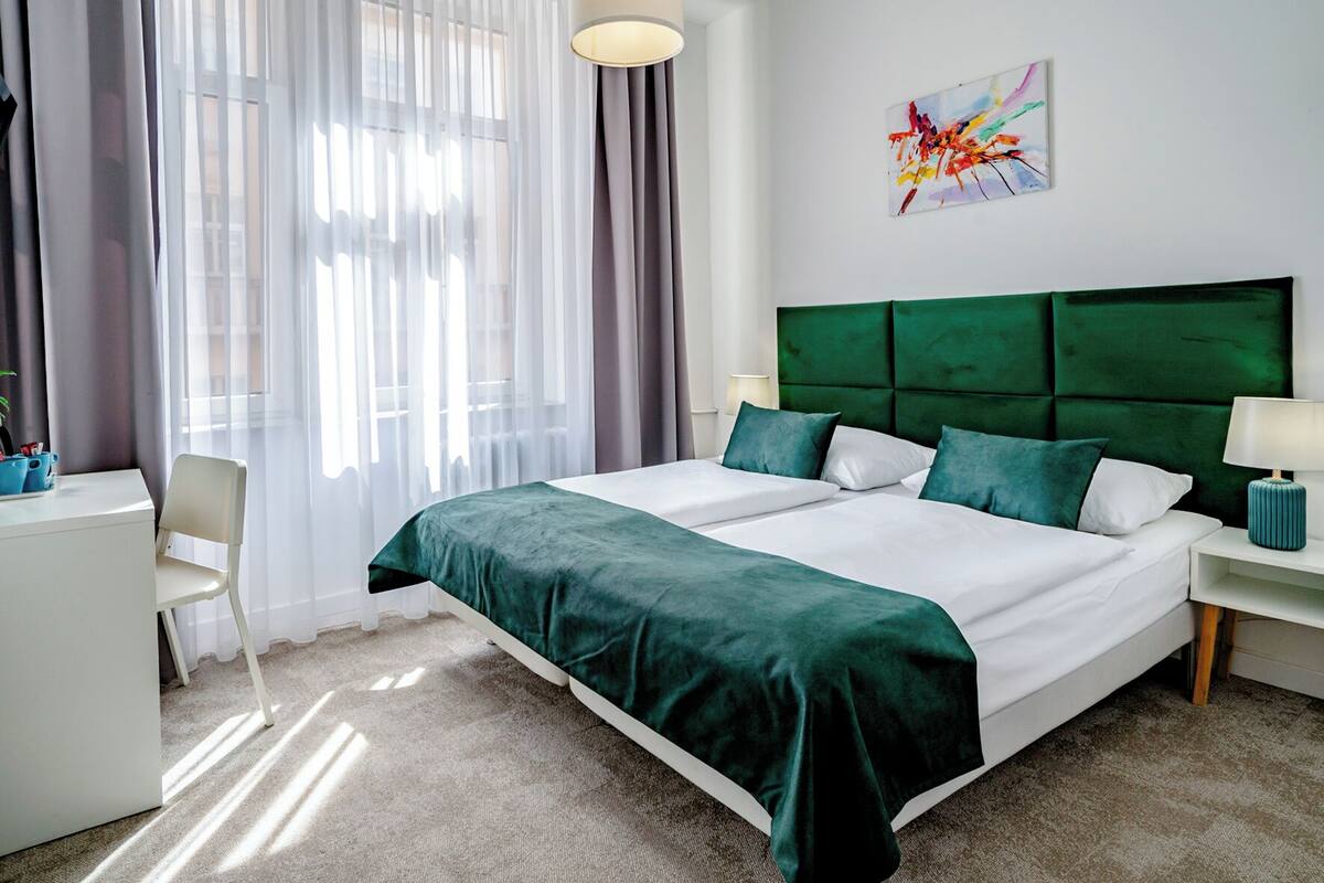 A neatly arranged hotel room with a large bed, a desk, and a chair.