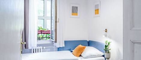 Um quarto com uma cama, uma mesinha de cabeceira com abajur, e duas molduras com quadros na parede.
