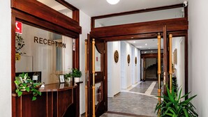 A reception area with a wooden reception desk, a mirror, and a staircase leading to another floor. - Elisabeth Old Town (Bratislava)