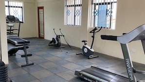 A gym with various exercise equipment including treadmills, an elliptical, and a stationary bike. - S. Lucie Mango Apartment (Nairobi)