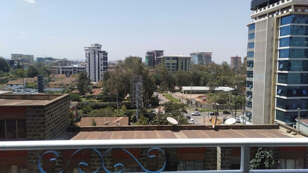 A cityscape with modern buildings, including a tall skyscraper with reflective glass windows. - S. Lucie Mango Apartment (Nairobi)