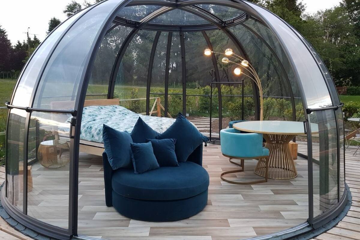 Eine durchsichtige Kuppelkonstruktion mit rundem Tisch und blauem Sofa im Inneren.