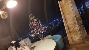A modern dining area with a round table, blue chairs, and a decorative Christmas tree. - La bulle au bois dormant d'ovifat (Waimes)