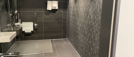 A modern bathroom with a shower, sink, and toilet.