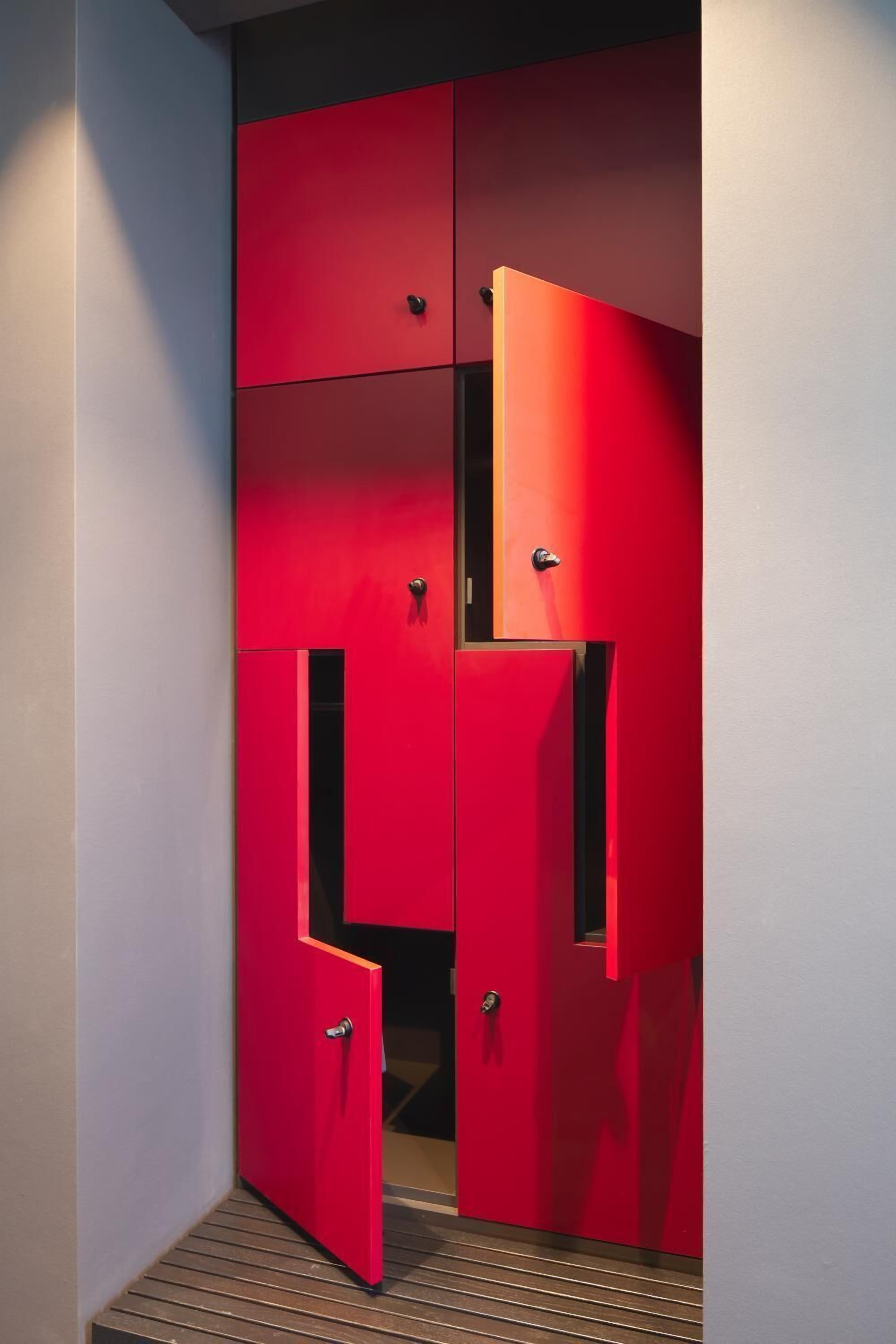 Guarda-roupa vermelho com vários compartimentos e uma pequena janela.