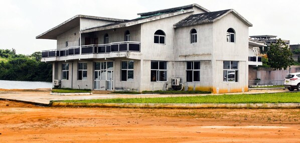 A two-story building with a balcony on the ground floor, large windows, and a flat roof. - Mabea Beach (Abidjan)