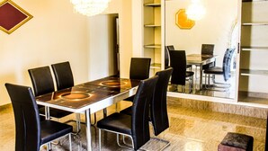 Un espace repas comprenant une table rectangulaire, six chaises noires, un lustre et un grand miroir qui reflète la pièce.