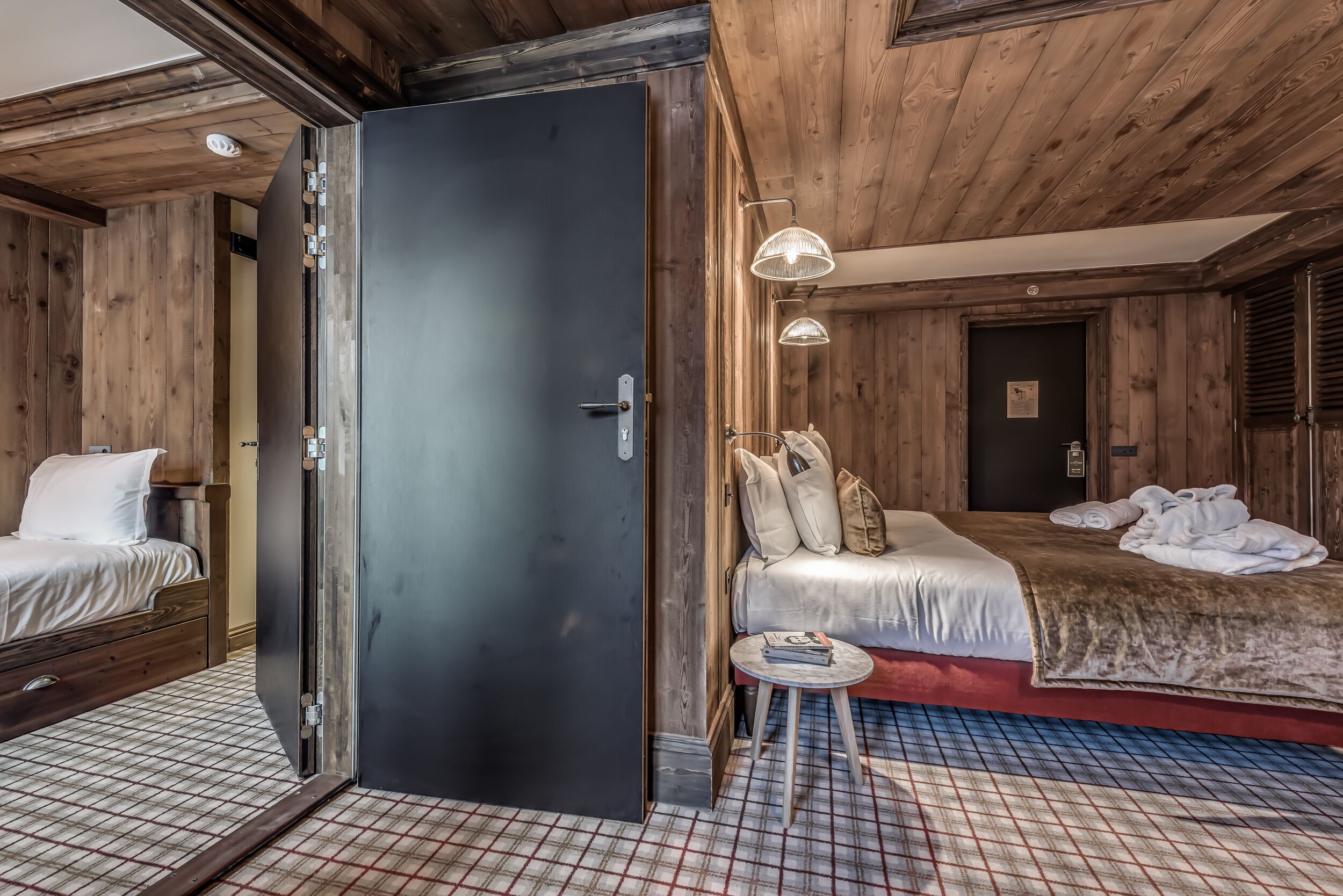 A wooden-themed hotel room with a bed, a small table, and a wardrobe.