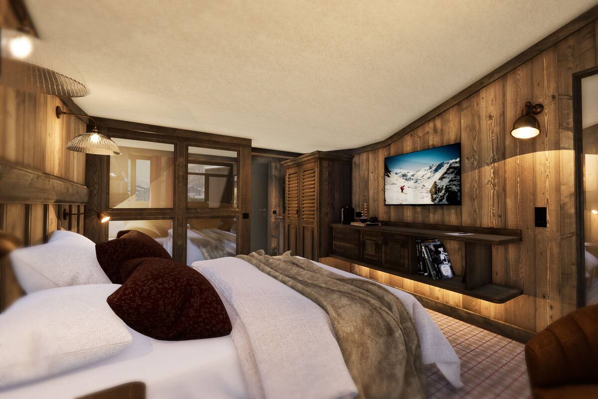 A modern bedroom with a large bed, wooden panel walls, a mounted TV, and a cozy seating area.