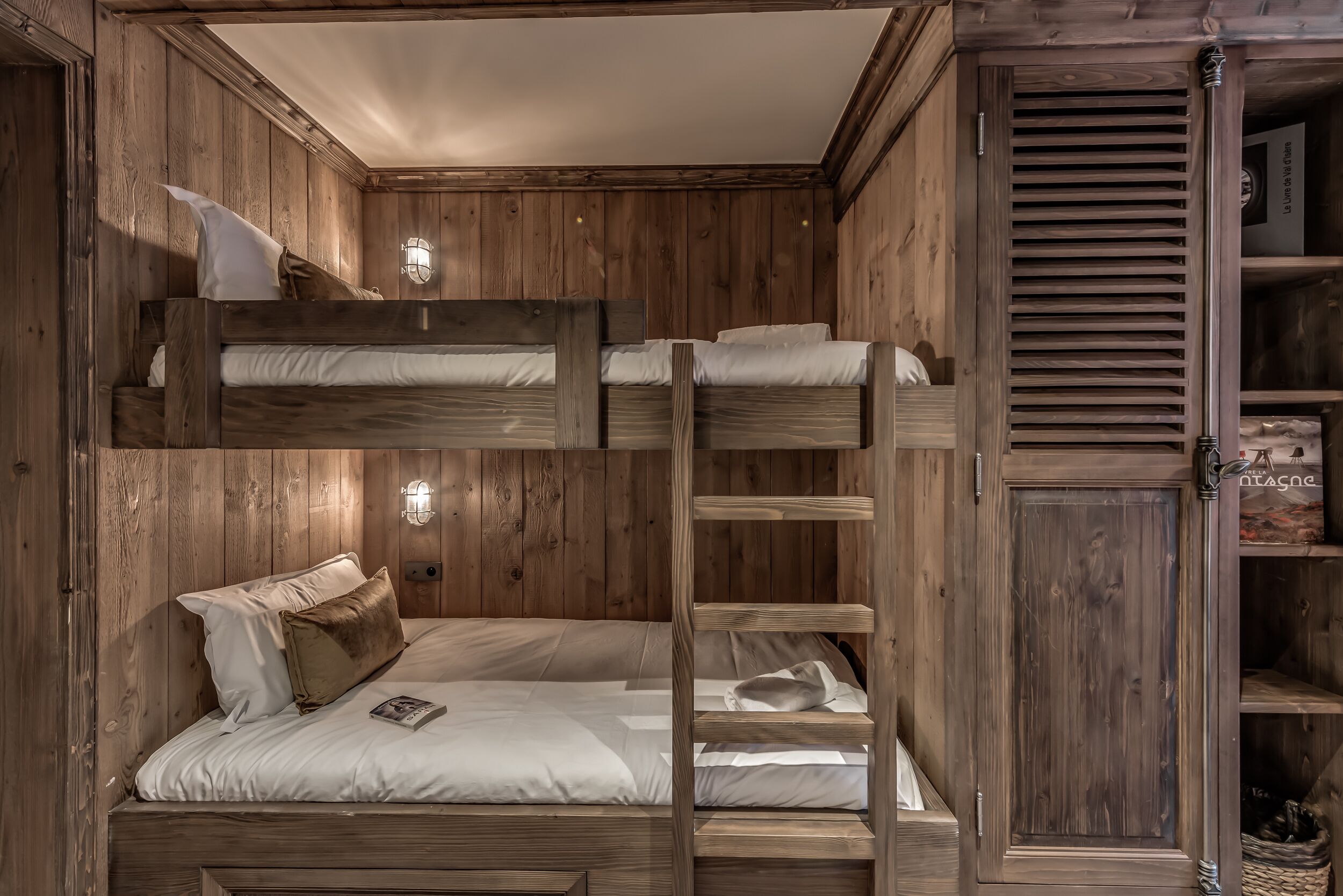 A bunk bed room with wooden walls and a slanted ceiling.