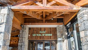 Ingresso di un hotel con tetto in legno e pareti in pietra, con un cartello che riporta la scritta "Hotel Leval d'Isere".