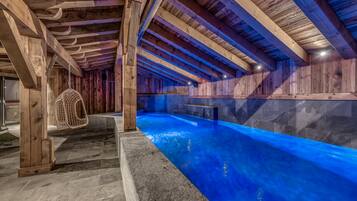 An indoor swimming pool with wooden beams and stone walls.