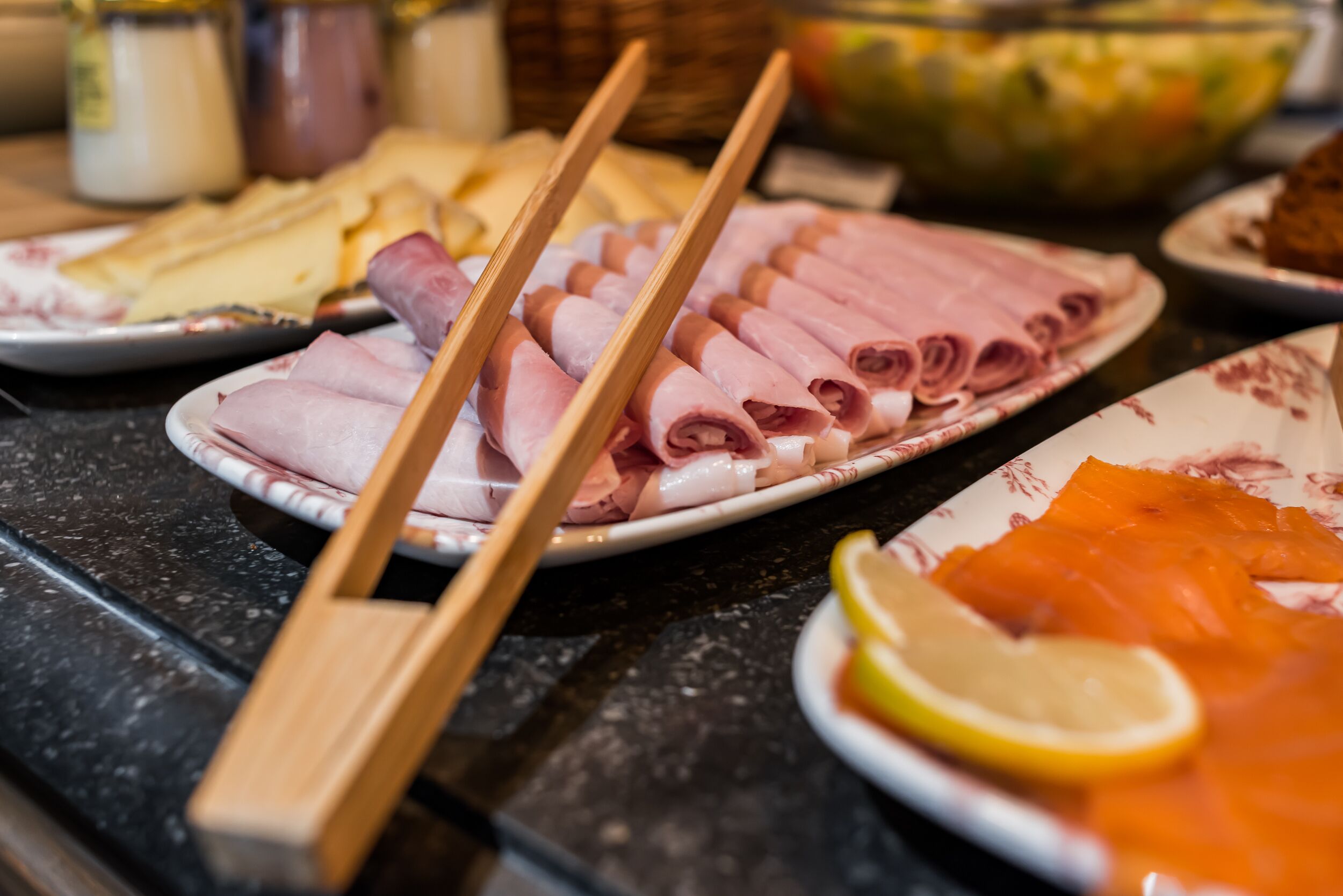 Une table de buffet proposant divers plats, notamment des viandes en tranches et un saladier de salade.