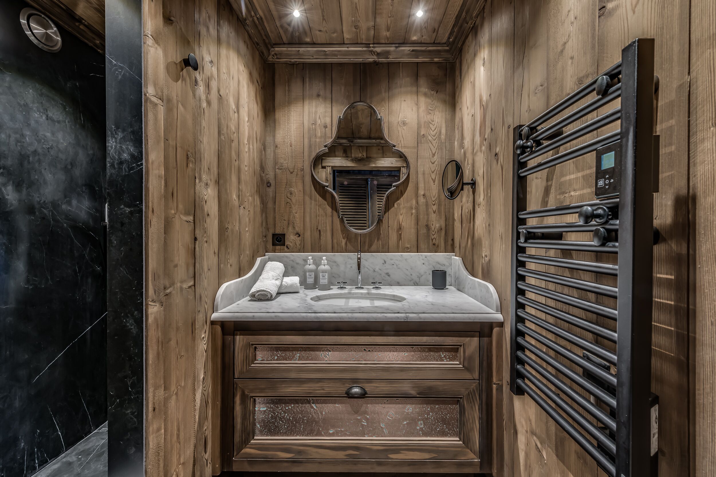 A wooden bathroom with a marble sink, wooden cabinets, and a towel rack.