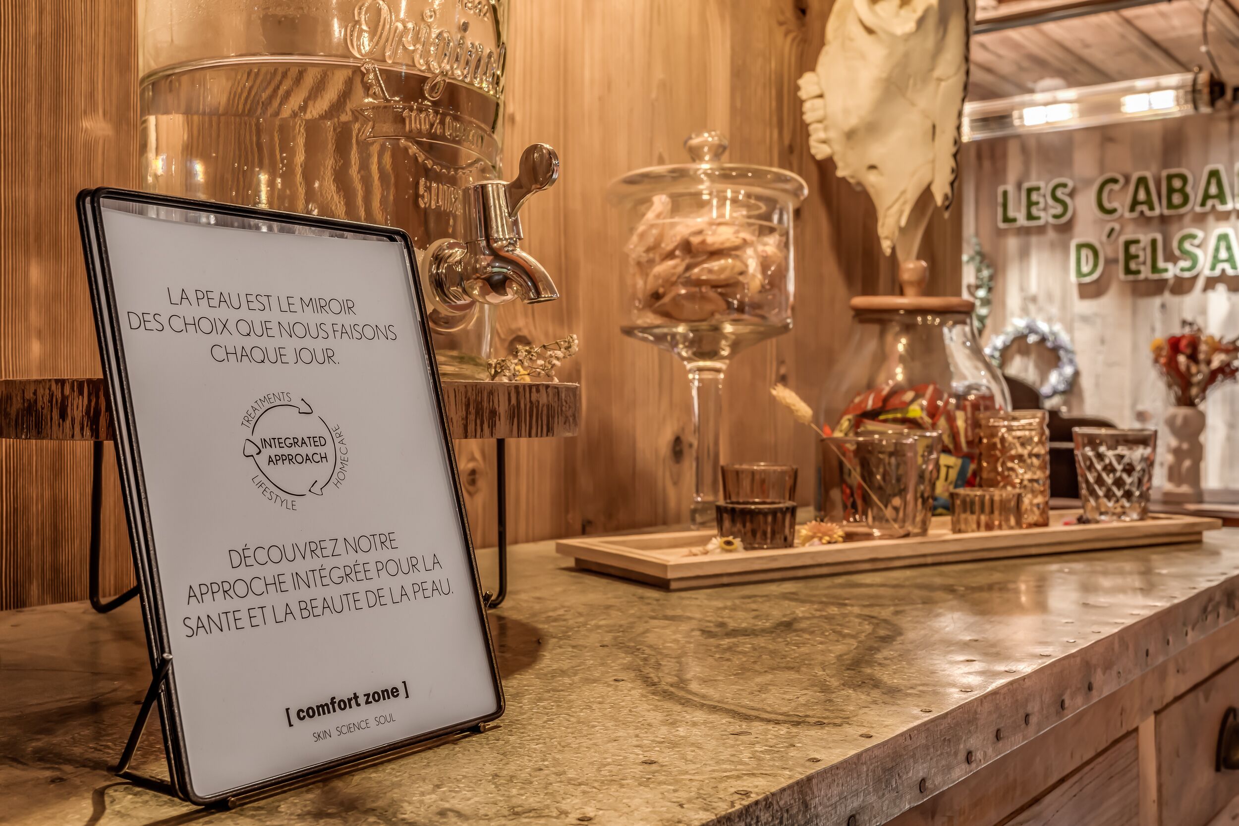 A sign in a cozy, wooden-themed room with a marble countertop, a glass jar, and a decorative glass container.
