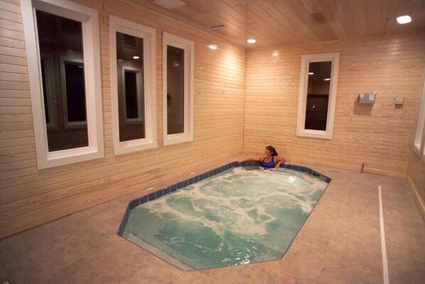 Quarto com decoração em madeira, banheira de hidromassagem e janela com vista.