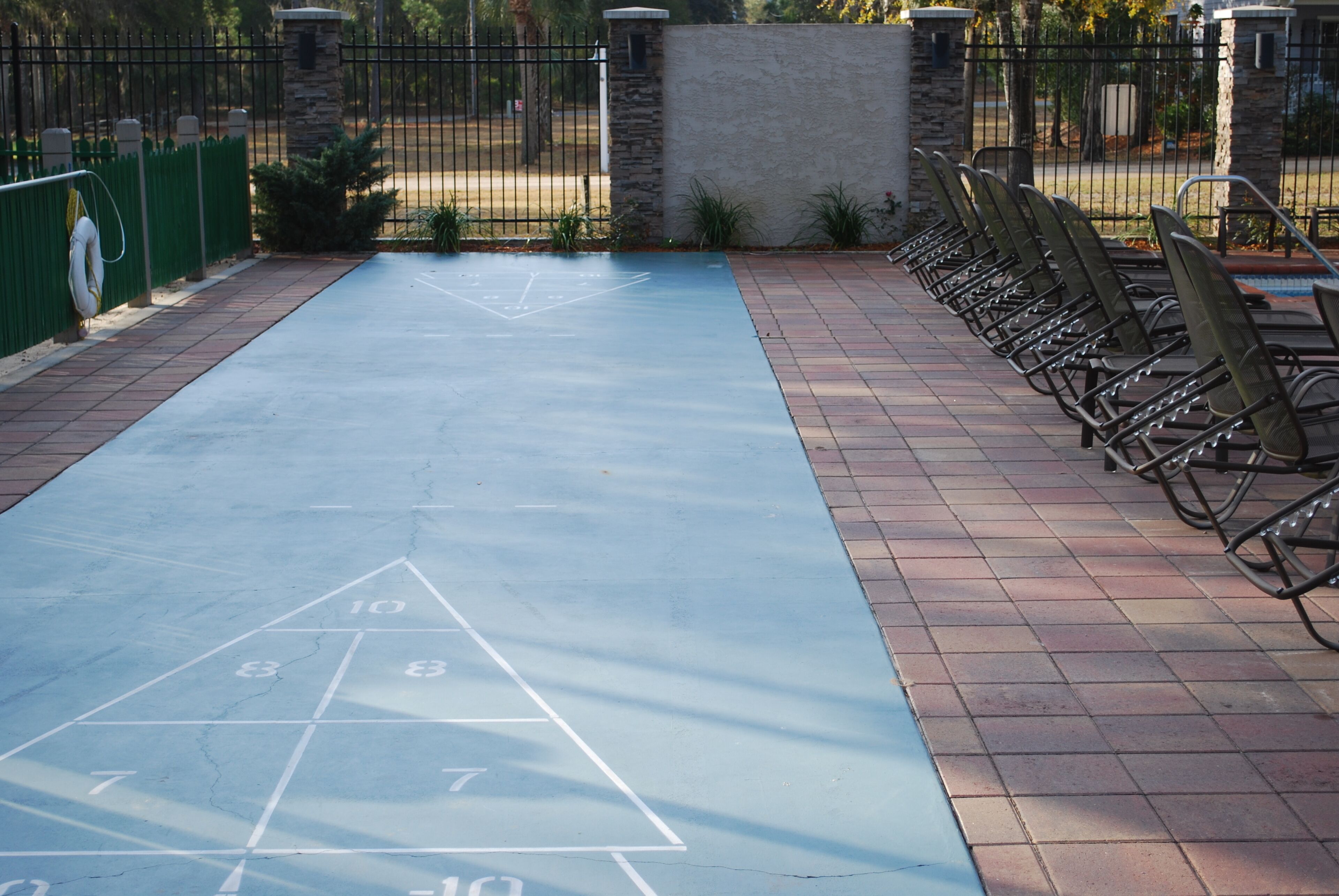 A hopscotch court with numbered squares and a metal fence in the background.